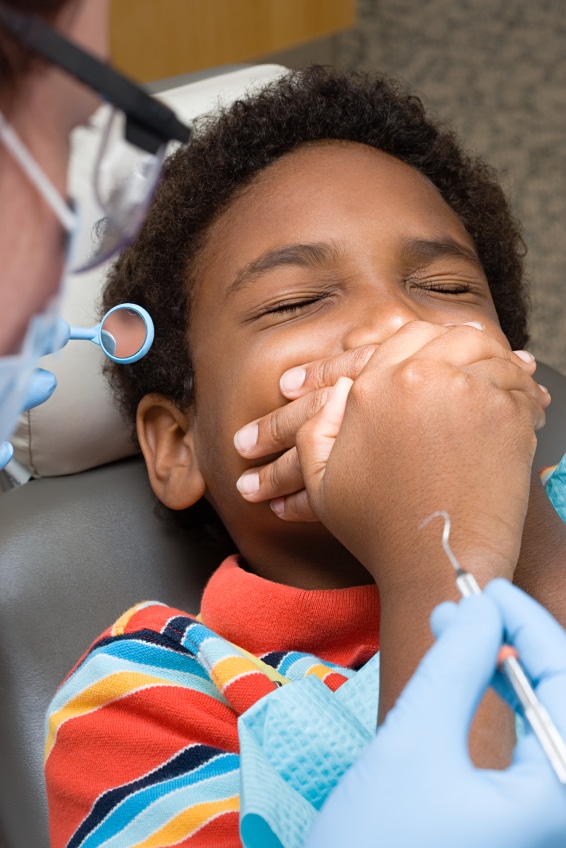 Boy covering mouth nervous about orthodontic procedure