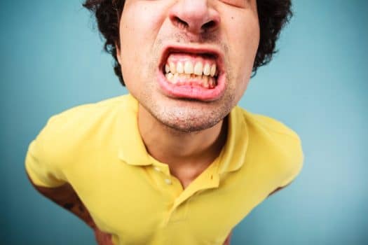 Man in a yellow shirt grinding his teeth