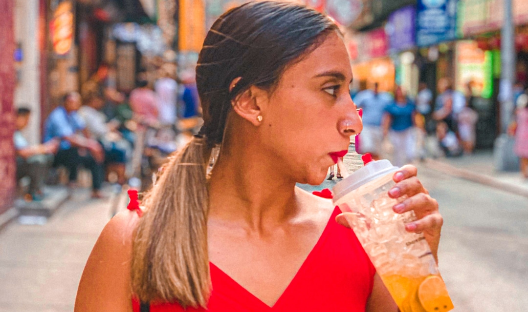 Profile of a woman with long hair drinking from a straw